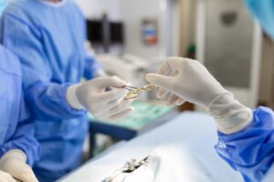 A cirurgia de retocele prevê a correção desse prolapso vaginal posterior a partir de técnicas diversificadas. Veja neste texto como o dr Luciano Teixeira, que é especialista em cirurgias para reparar más condições do assoalho pélvico, realiza esses procedimentos. Quando é indicada a cirurgia de retocele? A retocele é caracterizada quando há um enfraquecimento dos tecidos entre o reto e a vagina (chamado fáscia retovaginal) e as estruturas saem de sua posição normal. Dessa forma, o reto começa a se projetar em direção ao canal vaginal. Alguns conhecem a condição como uma hérnia intestinal na vagina. Um dado da Sociedade Americana de Cirurgia Colorretal indica que até 40% das mulheres podem ser atingidas por esse prolapso vaginal. No entanto, quem tem retocele, como está com o assoalho pélvico enfraquecido, pode sofrer também com outros prolapsos como de bexiga (cistocele) e útero. A correção cirúrgica de retocele deve acontecer quando o prolapso está em um nível avançado, provocando sintomas muito desagradáveis, como: Sensação de pressão retal; Dor retal; Peso na região genital ao evacuar; Necessidade de evacuar inúmeras vezes ao longo do dia; Sensação de não ter evacuado completamente; Incontinência fecal; Sensação de protuberância na vagina; Dores durante relação sexual; Sangramento vaginal. Segundo o dr Luciano Teixeira, quando a retocele está avançada e os sintomas impactam seriamente a qualidade de vida da mulher, a cirurgia é a única solução. O tratamento cirúrgico de retocele é indicado após exames para um diagnóstico preciso, como os exames clínicos realizados pelo urologista na região vaginal e anal. Além disso, outros procedimentos também irão atestar o grau da retocele como ressonância magnética, ultrassonografia, manometria retal e defecografia. O preparo do dia anterior à cirurgia envolve a ingestão de medicamentos para limpar o intestino, alimentação leve e jejum após a meia-noite ou na manhã antes do procedimento. Como é feita a cirurgia de retocele? O objetivo da cirurgia de retocele é sempre buscar alívio dos sintomas, além de melhorar as funções intestinais e também devolver a qualidade da vida sexual. Para realizar essa cirurgia, o paciente deverá tomar anestesia geral ou peridural e a internação é por cerca de 48 horas. O Dr. Luciano explica que a cirurgia de retocele promove o reforço da fáscia, por meio de uma reconstrução e plicatura das estruturas enfraquecidas que ocasionaram o prolapso. Para isso, serão utilizados fios de sutura e, para casos mais avançados, também pode ser necessário um material sintético (tela) para ajudar na sustentação. Especialista na cirurgia de cistocele e retocele, o Dr Luciano revela que os procedimentos podem se diferenciar pelas vias de acesso (transvaginal, transperineal ou transanal). Reparo transvaginal e perineal O reparo transvaginal da retocele é o tipo de procedimento mais tradicional entre os urologistas. Também denominado de reparo posterior, a retocele é alcançada através da vagina. Além do reparo da parede vaginal, essa via permite também o afinamento do períneo e da abertura da vagina alargada. Nesta cirurgia, é realizada uma incisão na parede posterior da vagina e a mucosa é separada da fáscia retovaginal. Então são reparados com pontos os locais onde a fáscia estava rasgada. Os pontos da cirurgia serão absorvidos naturalmente. Reparo transanal Neste tipo de reparo, a retocele é alcançada através do ânus e permite a correção dos problemas na região anal ou retal. As técnicas de correção são: Colpoperineorrafia: nesta técnica, é realizada a sutura da vagina e períneo lesados; Colporrafia posterior: há um reforço na sutura das paredes para promover estreitamento vaginal; Perineorrafia: o reforço é na região perineal com pontos mais profundos nos músculos que são presos nela. Há riscos na cirurgia de retocele? Segundo o Dr Luciano, todas as cirurgias envolvem algum tipo de risco, mas a expertise do médico pode minimizar muito as chances de complicações. Quando uma mulher faz uma cirurgia de retocele, alguns riscos são: Problemas anestésicos; Infecção; Sangramento; Dor em relações sexuais; Desenvolvimento de fístula entre o reto e a vagina; Recorrência da retocele. Para reduzir esses riscos, o médico também indica medicamentos, como analgésicos e antibióticos. Além disso, outro risco é a constipação intestinal após a cirurgia, para isso, também são indicados laxantes para ajudar no funcionamento intestinal. É aconselhado que as pacientes sigam as orientações pós-operatórias, fazendo repouso, não praticando atividades físicas (musculação, corrida, natação, andar de bicicleta, etc) e sexuais por 5 a 6 semanas, e não levantando pesos superiores a 5 quilos pelo mesmo período. As pacientes poderão voltar a dirigir e fazer pequenas caminhadas em 2 semanas. Dessa maneira, as probabilidades de um pós-operatório tranquilo são muito maiores, bem como uma recuperação mais rápida, embora alguns desconfortos nos primeiros dias sejam considerados normais. O sangramento por um certo período também é normal após a cirurgia de retocele, mas não é aconselhado o uso de absorventes internos. Uma consulta de acompanhamento da cirurgia também é orientada após cerca de 2 semanas. Porém, se antes disso, houver febre ou dor que não passam com os remédios, sangramento exagerado, não conseguir evacuar e ter náuseas e vômitos, é preciso acionar o médico. Muitos estudos revelam que há chances de uma melhora significativa de 90% nos sintomas da retocele após a cirurgia, a depender da gravidade dos sintomas e do tempo que a mulher conviveu com a patologia sem tratamento. Quais são as causas da retocele? Há como prevenir o quadro? Uma em cada 10 mulheres que tiveram partos múltiplos e instrumentais e são obesas vão realizar algum tipo de procedimento para correção de prolapsos vaginais. Porém, outras condições como o envelhecimento, hereditariedade, constipação intestinal e esforço crônico nas evacuações também podem contribuir para o surgimento de um quadro de retocele. Por isso, uma das formas de evitar o surgimento da patologia, é praticar exercícios físicos que reforcem o assoalho pélvico e realizar tratamento das condições crônicas do intestino, além de adotar uma dieta rica em fibras.
